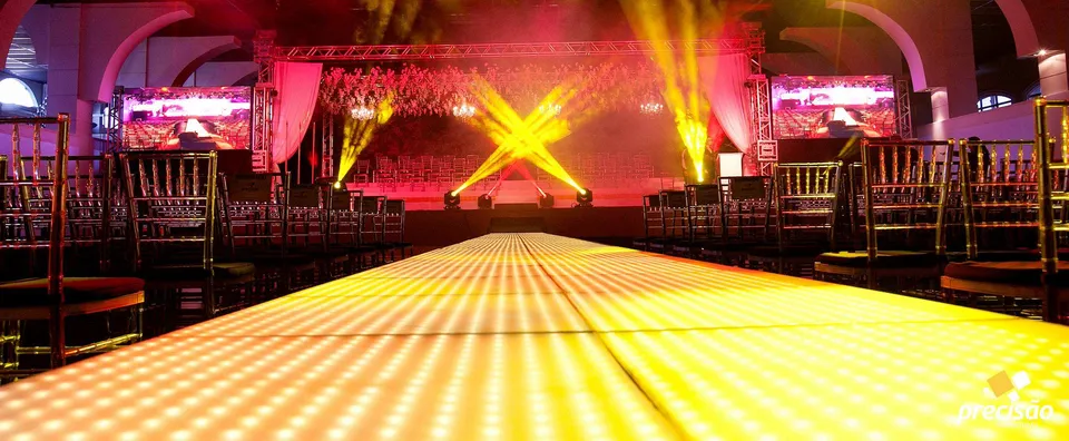 Passarela iluminada em amarelo com palco e estrutura de formatura