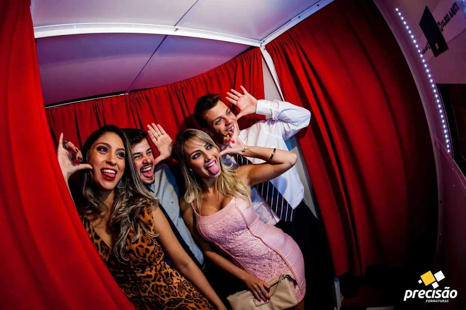 Amigos comemorando em cabine de fotos com cortina vermelha